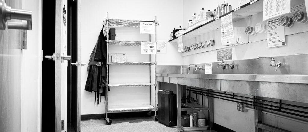The film processing lab: steel sinks, shelves of tanks and the film drying cabinet