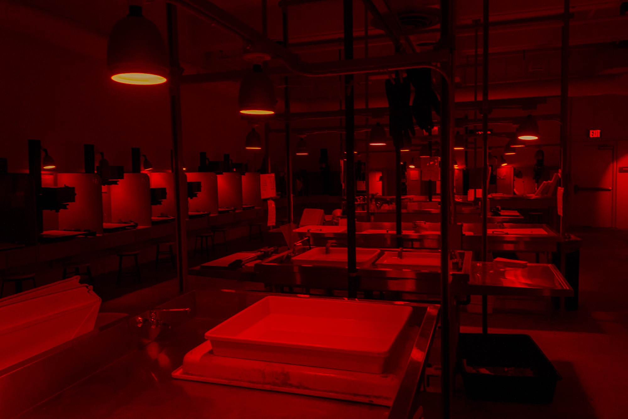 Enlarger stations lit by safelight in the black and white printing darkroom